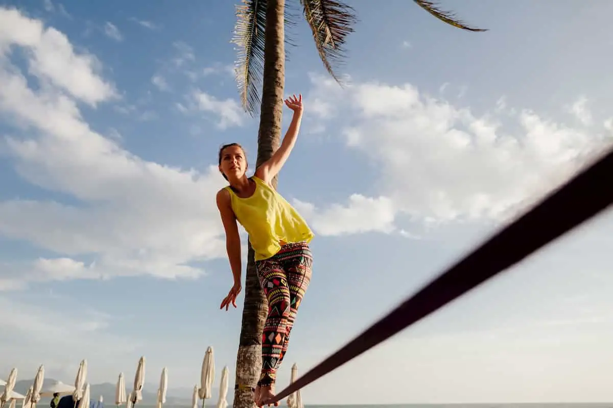 girl balancing on slackline with sky view - Is Slacklining a Good Workout?